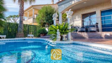 Piscina exterior con escalones de azulejos en Villa Grace, que cuenta con columnas decorativas, estatuas y una palmera en el jardín.