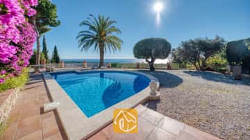 Piscina privada en Villa Gabriella con vistas al mar, una palmera y una estatua de Buda de piedra en la terraza alicatada.