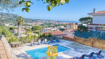 Piscina privada de aguas azuladas y tumbonas en su entorno, con vistas al pueblo y al mar, en Villa Abigail