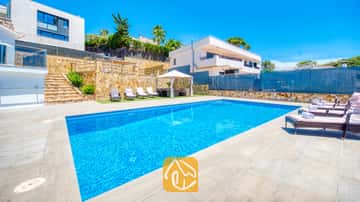 Piscina privada en la Villa SummerDream de aguas azul brillante, rodeada de muros de contención de piedra, patio enlosado y bordeada de tumbonas.
