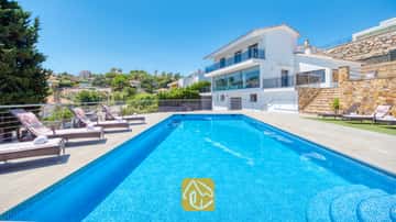 Piscina rectangular con azulejos de mosaico azul y múltiples tumbonas en la terraza pavimentada de Villa SummerDream en España.