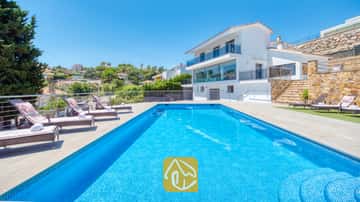 Piscina rectangular con azulejos de mosaico azul y múltiples tumbonas en la terraza pavimentada de Villa SummerDream en España.