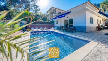 Piscina privada y terraza en Villa Zarita, que cuenta con una piscina de azulejos azules, tumbonas blancas y un juego de comedor al aire libre bajo un toldo azul.
