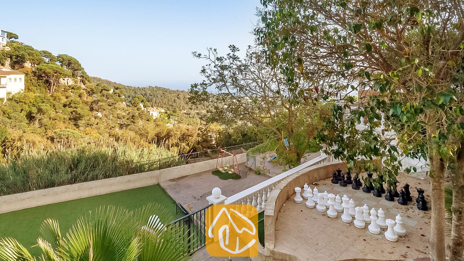 Gigantesco juego de ajedrez al aire libre en una terraza de piedra en Villa Tropicana, con vista a verdes colinas y árboles