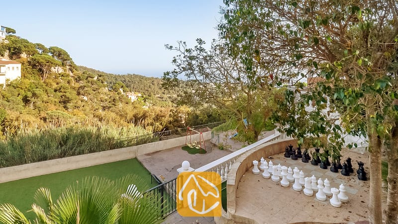 Gigantesco juego de ajedrez al aire libre en una terraza de piedra en Villa Tropicana, con vista a verdes colinas y árboles