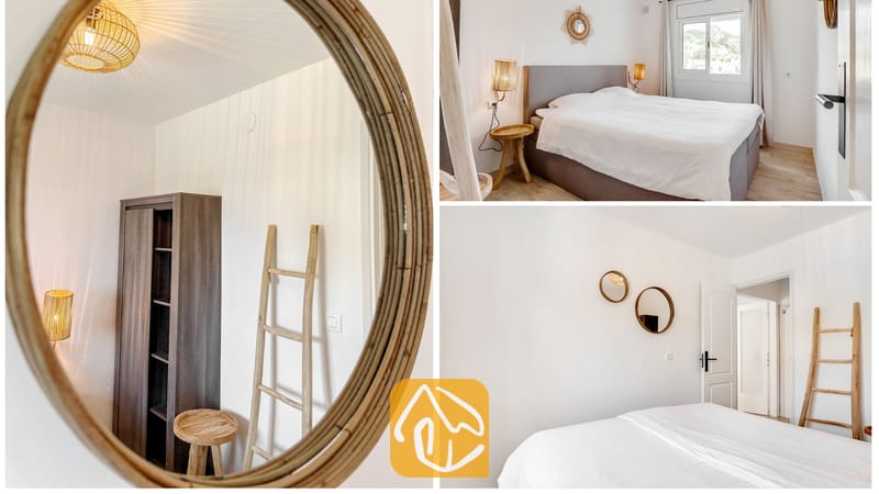 Interior del dormitorio con una cama con ropa de cama blanca, una escalera decorativa de madera y espejos de pared redondos.
