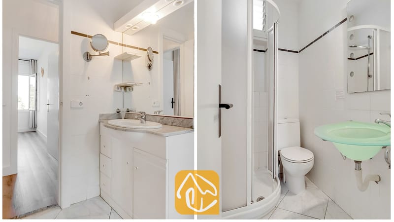 Baño luminoso de azulejos blancos con lavabo integrado en mueble tocador, un gran espejo de pared y una cabina de ducha esquinera al lado.