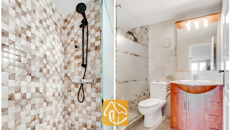 Mod cuarto de baño moderno cuenta con una ducha a ras de suelo con grifería negra, azulejos de mosaico en tonos neutros, un inodoro blanco y un mueble de madera con lavabo integrado y espejo.