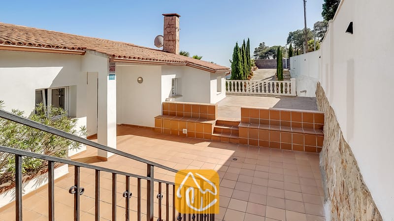 Terraza exterior de Villa Tropicana con suelo de baldosas, bancos de cerámica empotrados y una chimenea de piedra bajo un cielo azul despejado