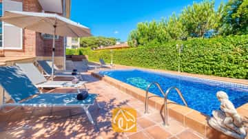 Piscina exterior privada en Villa Beyoncé de aguas cristalinas, con barandillas metálicas y una estatua de piedra junto a una hilera de tumbonas grises en una terraza enlosada.