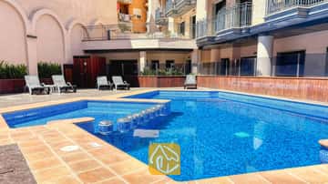 Piscina exterior con azulejos de mosaico azul y tumbonas en el Apartment Dali, rodeada de edificios residenciales de varias plantas con balcones.